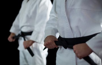Mid Section Of Two Karate Fighters Performing Karate Stance Against Black Background